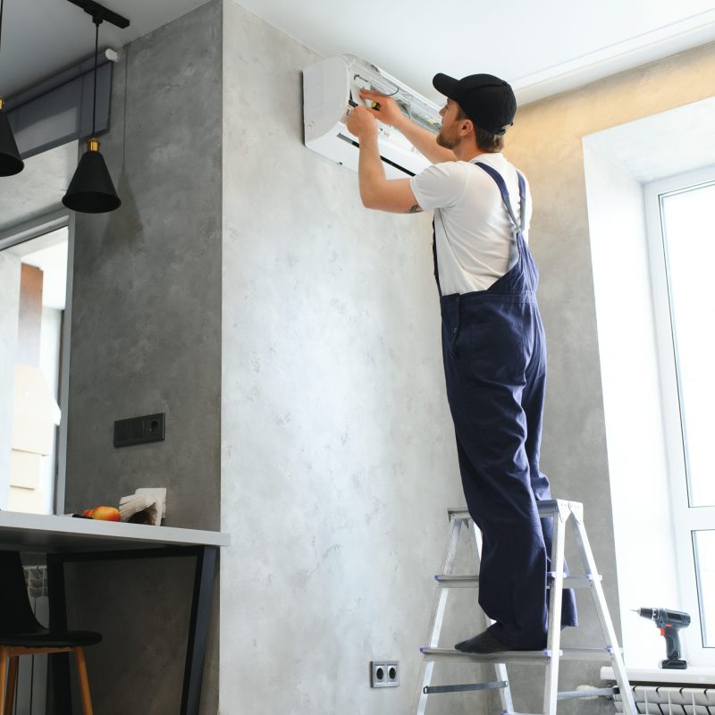 Happy Male Technician Repairing Air Conditioner