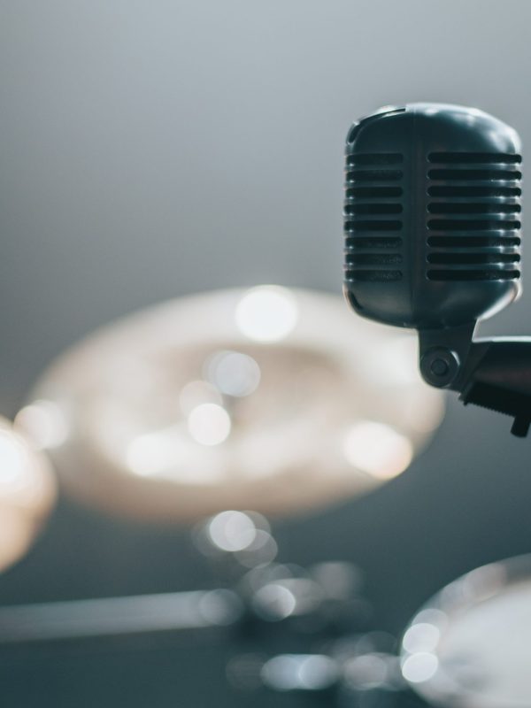 Microphone on a stage with a drum set in the background on a concert